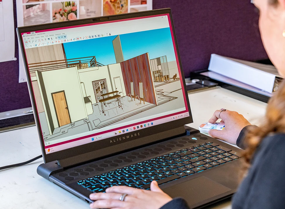 Interior design student works on a building design in a 3D application on her laptop
