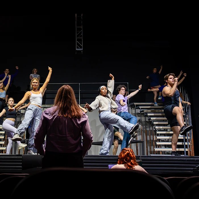 Students rehearse a stage performance while being coached by their instructor