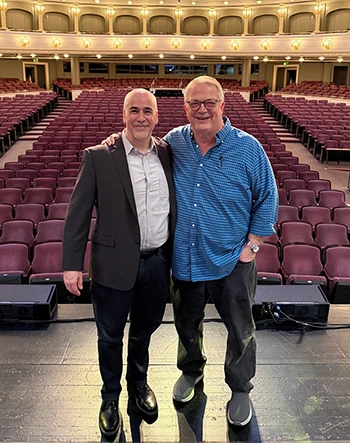Peter Boyer & Harry Parker stand on stage, backs to the seats, at Bass Hall in Fort Worth