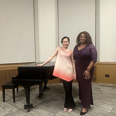Gwendolyn Alfred and Cecilia Lo-Chien Kao stand in front of a grand piano